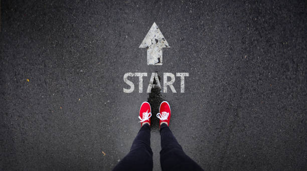 Red shoes standing next start with arrow painted on ground  resume stock pictures, royalty-free photos & images
