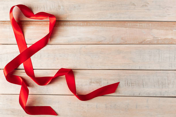 Red silk ribbon in shape of a heart on a wooden background. Valentine's day concept. Place for text. stock photo