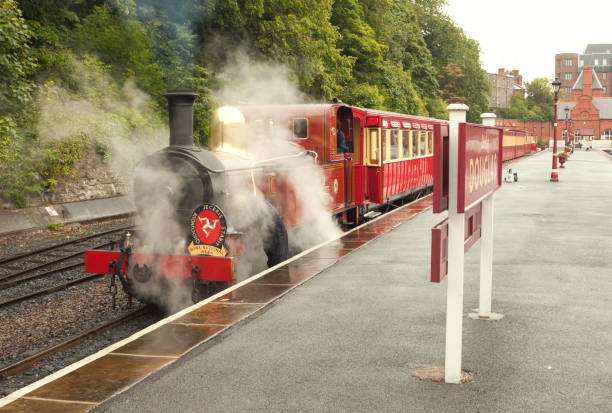 Red steam locomotive with train of IMR line in puffs of vapour. Douglas, Isle of Man, UK stock photo