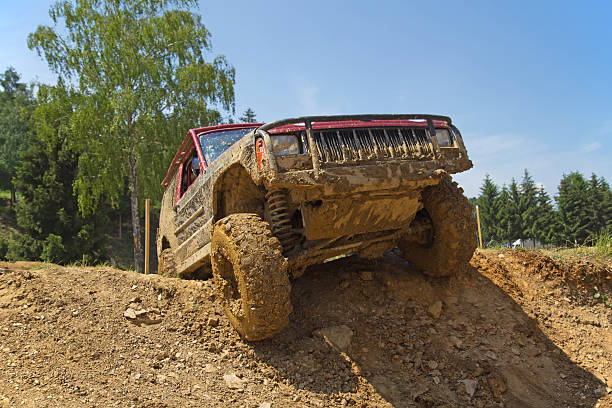 Red SUV overcomes steep muddy slope. stock photo