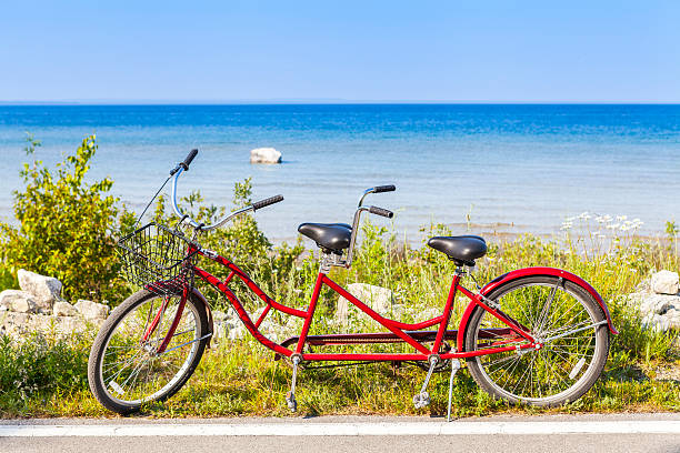 Red tandem bicycle on the side of a road by a beach Red Tandem mackinac island stock pictures, royalty-free photos & images