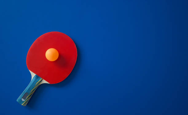 Red tennis racket with yellow ball Red tennis racket lies on a blue table with a yellow ball table tennis stock pictures, royalty-free photos & images