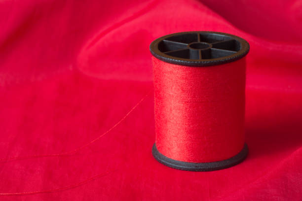 Red thread on bright red fabric background stock photo