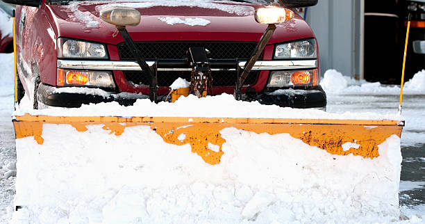 red truck with snow plow clearing pavement stock photo