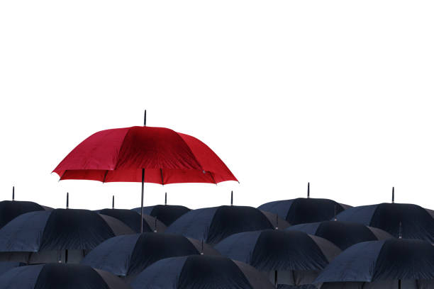 Red umbrella stand out from black umbrellas on studio stock photo