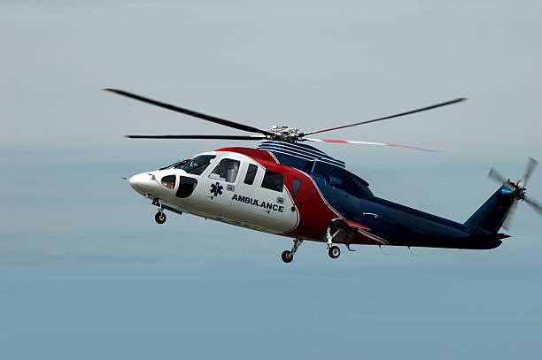 A red, white and blue air ambulance helicopter An air ambulance rescue helicopter arriving at an accident scene. emergency response stock pictures, royalty-free photos & images