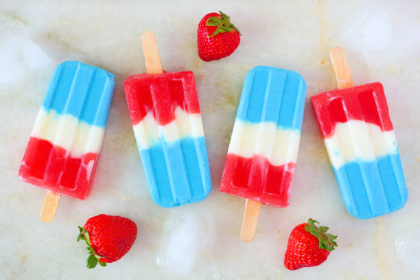 Red, white and blue summer ice pops on a white marble background stock photo