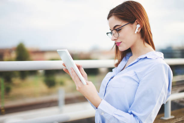 Redhead young businesswoman using tablet outdoors stock photo