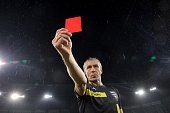 Referee showing red card during football match.