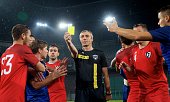Referee showing yellow card during football match.