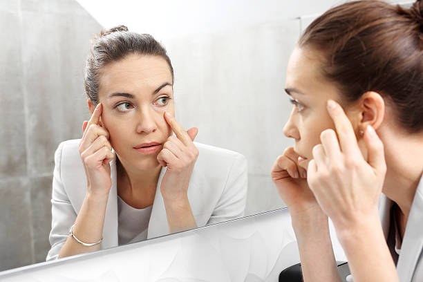 Reflection in the mirror. Reflection in the mirror. Woman looks in the mirror noticing the first wrinkles tired stock pictures, royalty-free photos & images