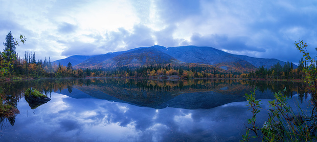 Reflection of mountains and clouds in the calm surface of the lake. Peaceful landscape. Khibiny. photo