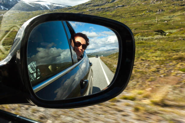 Reflection of the woman in the car mirror on the road in Norway stock photo