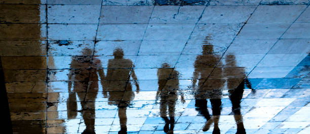 silhouette d'ombre de réflexion sur le trottoir humide de ville des personnes mystérieuses marchant loin la nuit - night lugage photos et images de collection