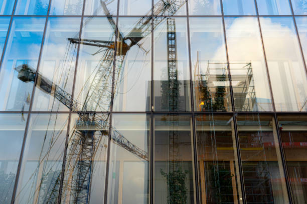 reflektioner av en frane och byggarbetsplats i glasfasaden av en kontorsbyggnad. - byggarbetsplats sverige bildbanksfoton och bilder