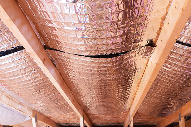 Reflective Radiant Heat Barriers Between Attic Joists Used as Ba Insulating of attic with fiberglass cold barrier and reflective heat barrier used as baffle between the attic joists to increase the ventilation to reduce humidification construction barrier stock pictures, royalty-free photos & images