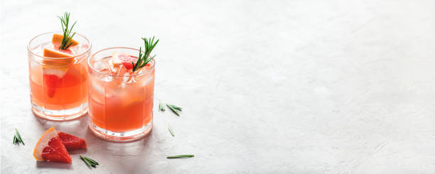 Refreshing grapefruit cocktail with ice and rosemary. Refreshing grapefruit cocktail with ice and rosemary on a grey background. cocktail stock pictures, royalty-free photos & images