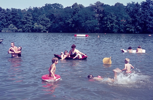 West Germany (exact location unknown), 1977. Families splash in the water of a lake in a local recreation area on a hot summer's day.