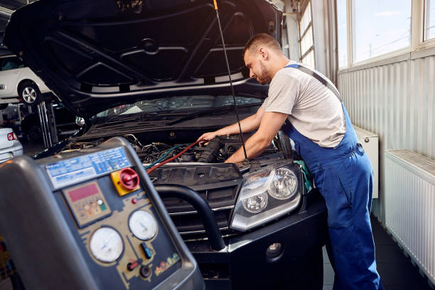 Refueling the air conditioner. A mechanic pumps freon into the air conditioning system at a car service. stock photo