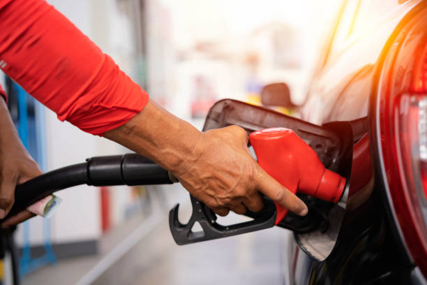 Refueling the car at a gas station fuel pump. Man driver hand refilling and pumping gasoline oil the car with fuel at he refuel station. stock photo