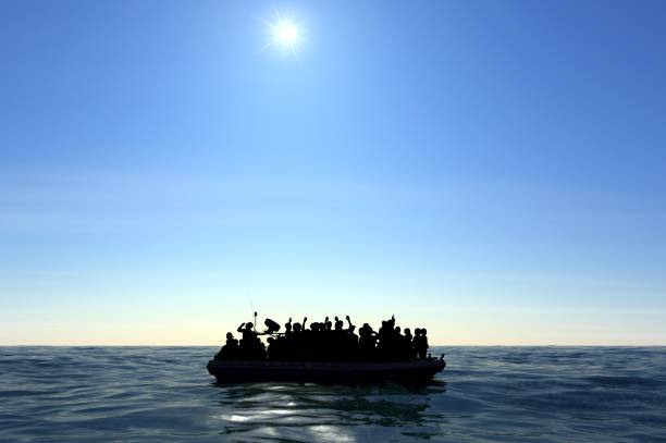 Refugees on a big rubber boat in the middle of the sea that require help stock photo