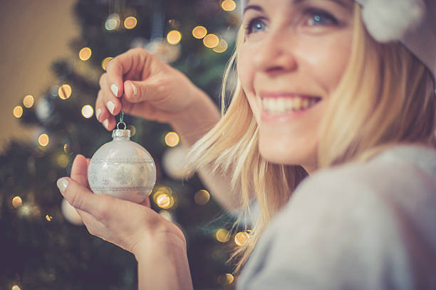 regional christmas at home - blonde woman decorating xmas tree - vrouw kerstboom versieren stockfoto's en -beelden