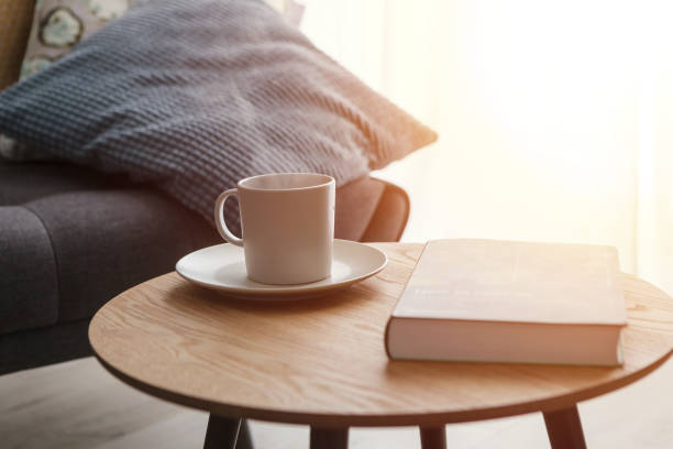 Relax at home, cup of hot tea and book on coffee table by the sofa stock photo