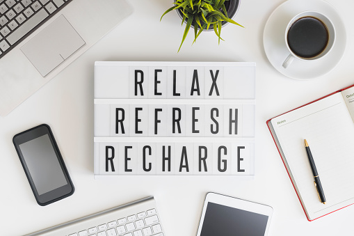 Relax, refresh and recharge words on office table with computer, coffee, notepad, smartphone and digital tablet