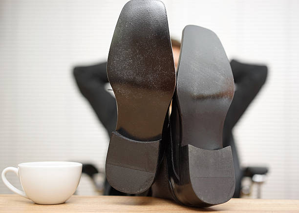 empresário relaxado está sentado com os pés na mesa - business man shoes on desk imagens e fotografias de stock