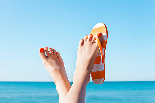 relaxed woman feet and flip flops on the beach - voeten in het zand stockfoto's en -beelden