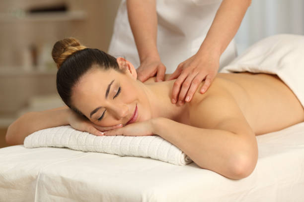 Relaxed woman receiving massage in a salon Relaxed woman receiving a back massage in a spa salon massage therapist stock pictures, royalty-free photos & images