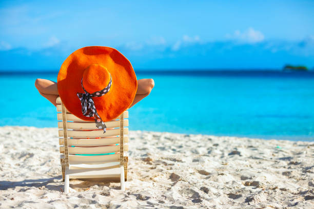 Relaxed young woman with orange hat sitting and sunbathing on a tropical turquoise Caribbean cay beach Relaxed young woman with orange hat sitting and sunbathing on a tropical turquoise Caribbean cay beach hot latino girl stock pictures, royalty-free photos & images