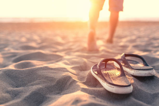 ontspannen in de buurt van de zee bij zonsondergang - voeten in het zand stockfoto's en -beelden