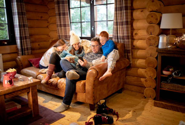 Relaxing on the Sofa A family relax on the sofa in a log cabin and use a smartphone. log cabin stock pictures, royalty-free photos & images