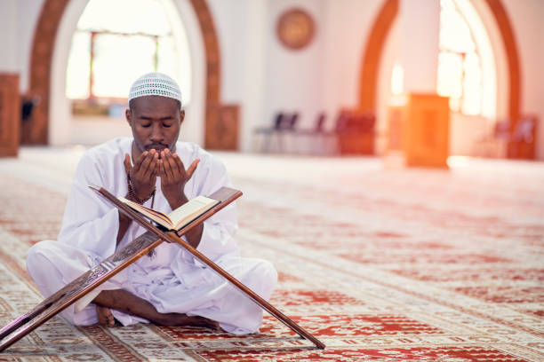 Religious black Muslim man praying inside the mosque stock photo