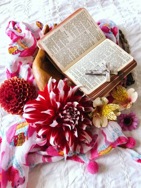 Religious Morning Prayer Background Wooden hands hold a vintage Bible book open at the Psalms  for a Religious Morning Prayer Background surrounded by flowers and a religious cross. good friday stock pictures, royalty-free photos & images