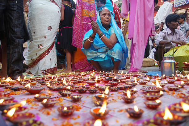 Religious Culcutta , India- November 12, 2010:Indian Hindu Devotees pay obeisance to both the rising and the setting sun in the Chhath Puja festival , when people express their thanks and seek the blessings of the forces of nature, mainly the Sun and river. In this occasion  a senior woman seating  front of the oil lamp . chhath stock pictures, royalty-free photos & images