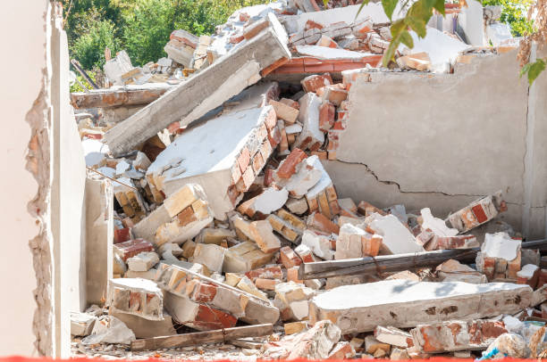 Remains of hurricane or earthquake disaster damage on ruined old house with collapsed roof and walls on the pile stock photo