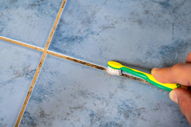 Removing mold from a grout in the bathroom with a toothbrush Moldy tile joints are scrubbed with a toothbrush tile joint cleaning stock pictures, royalty-free photos & images