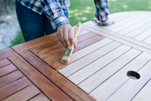 renovation of a garden table with a paintbrush and oil by a young girl stock photo