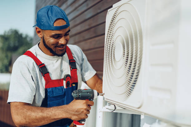 Repairman in uniform installing the outside unit of air conditioner stock photo