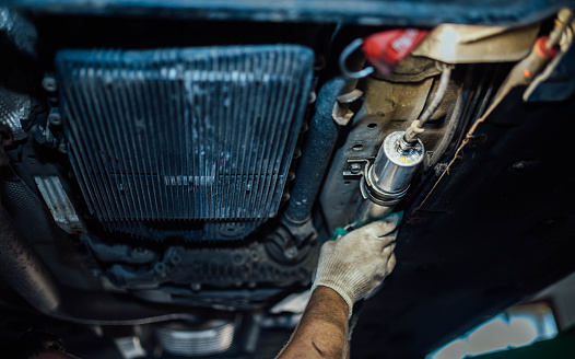 Replacing the fuel filter of a diesel car in a car service, dismantling the fuel filter under the bottom of the car.