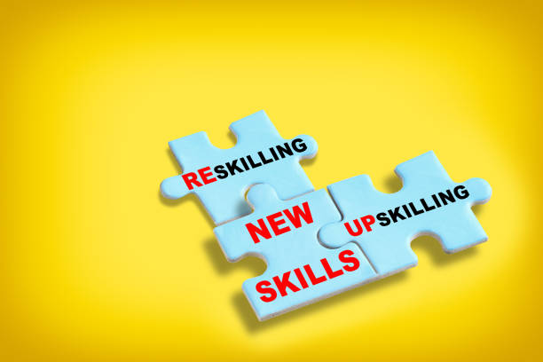 Reskilling, upskilling and new skills written on blue puzzle isolated on yellow background stock photo