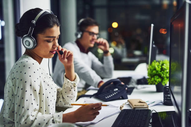 Resolving issues with speed for their clients Shot of young call centre agents working late in an office call center photos stock pictures, royalty-free photos & images
