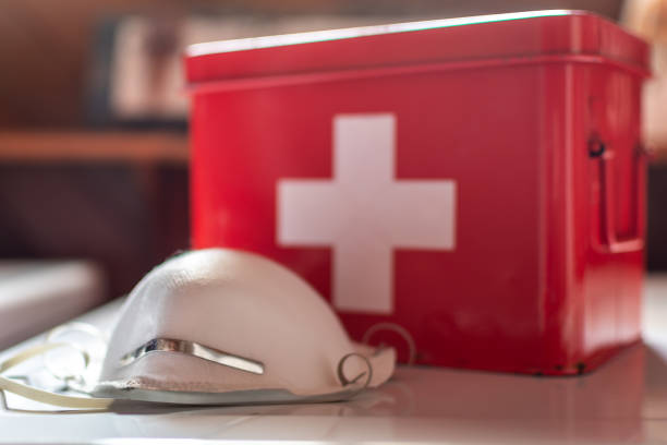 N95 respirator and first aid kit. N95 face mask next to a red first aid kit. first aid stock pictures, royalty-free photos & images
