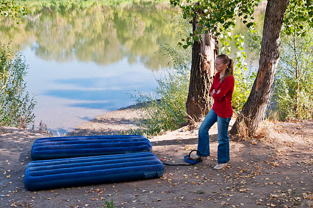 Rest at nature. Girl pumps up an inflatable mattress stock photo