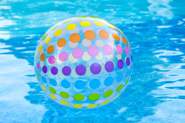 rest, lifestyle and summer swimming concept - closeup on surface of blue pool water with inflatable transparent ball decorated by colorful circles, entertainment in hotel or backyard of household stock photo
