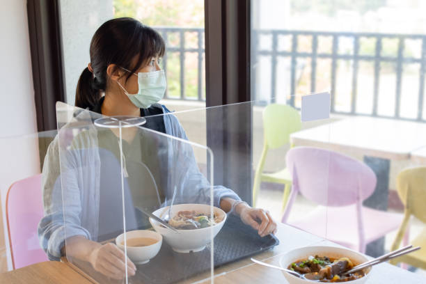 An Asian lady seated close to windows made using plexiglass