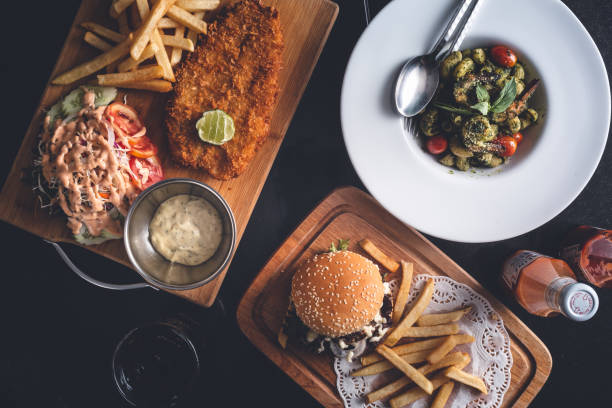 Restaurant Table with a Fish and Chips, Hamburger and Fries, Pasta Dish stock photo