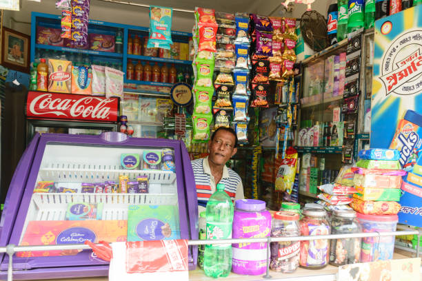 A retail grocery shop owner looking for customer from inside his store. Kolkata, West Bengal, India Kolkata, West Bengal, India 1st January, 2019 - A retail grocery shop owner looking for customer from inside his store. bengali sweets stock pictures, royalty-free photos & images